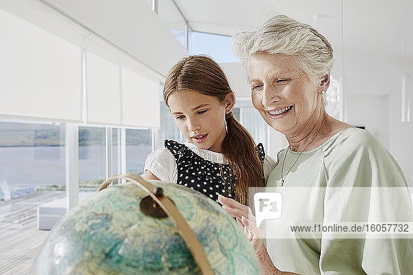 Großmutter und Enkelin betrachten den Globus in einer Villa