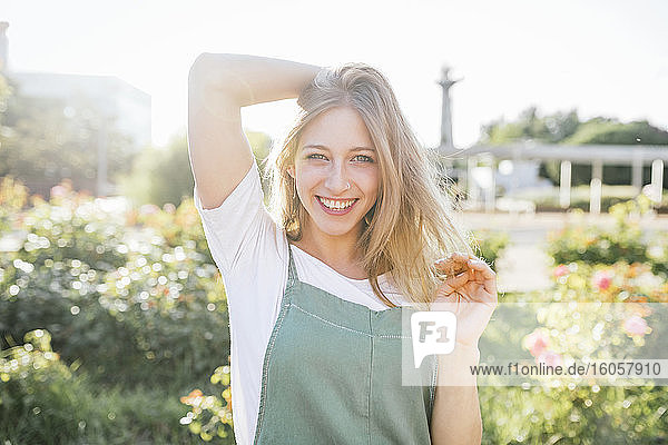 Porträt einer glücklichen jungen Frau im öffentlichen Garten bei Gegenlicht