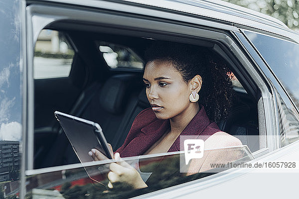 Junge Geschäftsfrau mit digitalem Tablet durch Autofenster gesehen