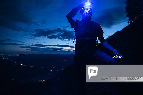 Male hiker with headlamp looking up while standing on mountain at night  Orobie  Lecco  Italy