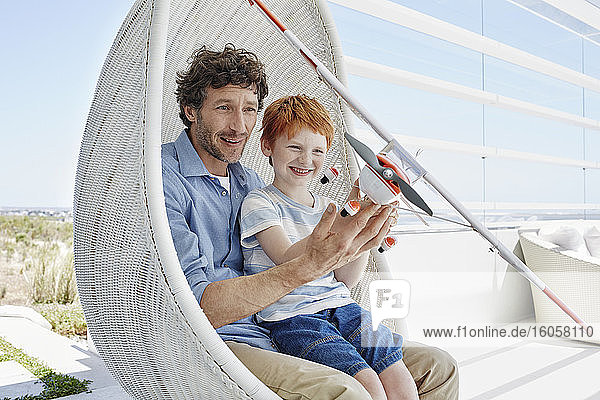 Glücklicher Vater und Sohn spielen mit Modellflugzeug im Hängesessel