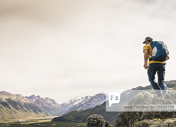 Älterer Wanderer mit Rucksack  der auf einem Felsen gegen den Himmel läuft  Patagonien  Argentinien