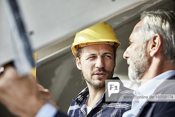 Architekt und Arbeiter im Gespräch am Fenster auf einer Baustelle