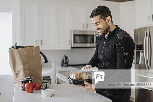 Smiling man cleaning groceries in kitchen at home