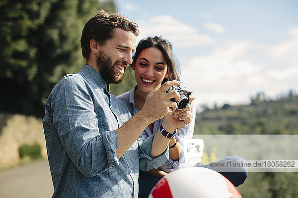 Close-up of happy couple looking pictures in camera