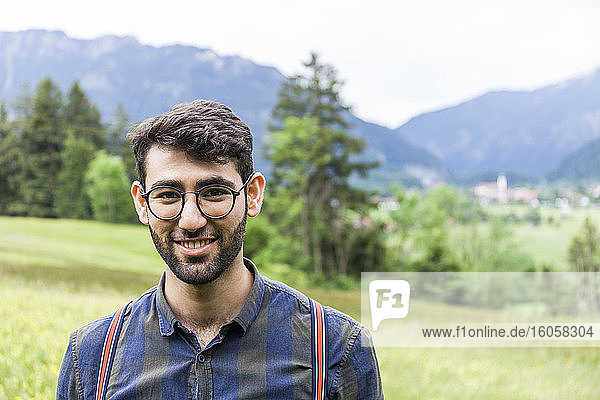 Porträt eines lächelnden jungen Mannes mit Brille  Reichenwies  Oberammergau  Deutschland