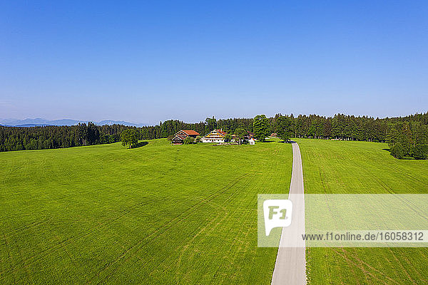 Deutschland  Bayern  Reit im Winkl  Drone view of dirt road leading to small countryside village in spring