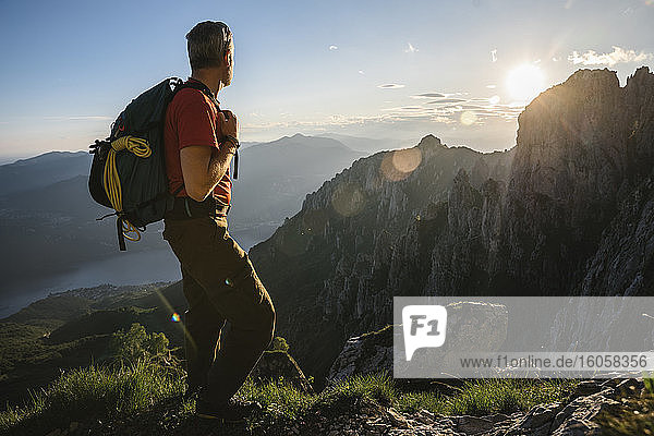 Männlicher Wanderer mit Rucksack mit Blick auf die Berge bei Sonnenuntergang  Orobie  Lecco  Italien