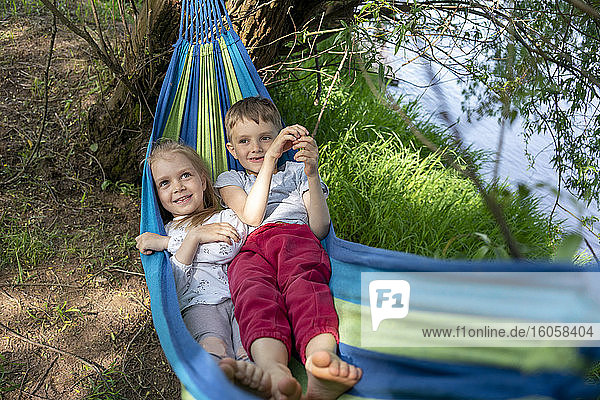 Cute children relaxing on hammock in forest