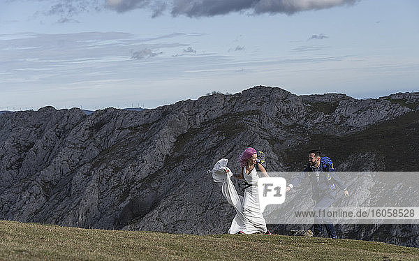 Brautpaar mit Kletterrucksäcken auf der Wiese