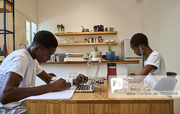 Young couple studying on table while sitting at home