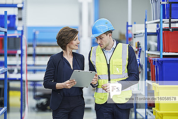 Supervisor and female manager discussing over clipboard in factory
