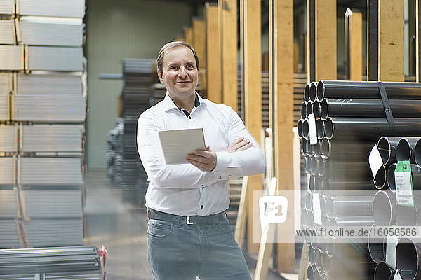 Smiling businessman holding tablet in a factory