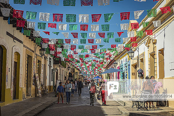 Girlanden  die über eine Straße zwischen Gebäuden und Fußgängern gespannt sind; San Cristobal de las Casas  Chiapas  Mexiko