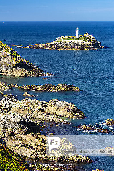 Weißer Godrevy-Leuchtturm auf einer Felsformation im blauen Wasser mit blauem Himmel und felsiger Küstenlinie  Godrevy Island in der St. Ives Bay; Grafschaft Cornwall  England