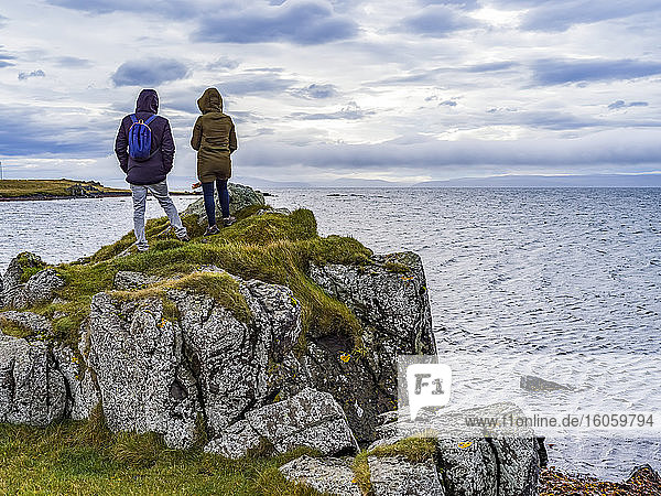 Ein Mann und eine Frau Touristen stehen auf einem felsigen Bergrücken mit Blick auf den Ozean und die Küste in Nordisland; Hunathing vestra  Nordwestliche Region  Island