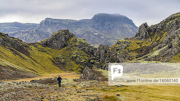Ein Wanderer auf einem Pfad mit einer rauen  weiten Landschaft im Hintergrund; Grimsnes- og Grafningshreppur  Südliche Region  Island