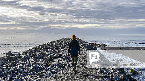 Eine Frau geht in Südisland in der Nähe der Stadt Vik in Richtung Ozean; Myrdalshreppur  Südliche Region  Island