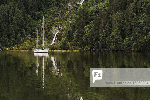 Segelboot im Great Bear Rainforest mit einem Wasserfall entlang der Küste; Hartley Bay  Britisch-Kolumbien  Kanada