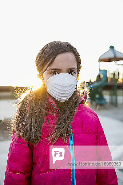 Junges Mädchen steht auf einem Spielplatz und trägt eine Schutzmaske zum Schutz vor COVID-19 während der Coronavirus-Weltpandemie; Toronto  Ontario  Kanada