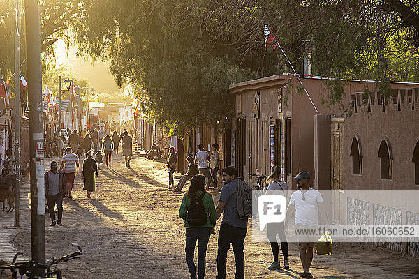 Das goldene Licht am Ende des Tages beleuchtet eine belebte Fußgängerzone in einer hoch gelegenen südamerikanischen Stadt; San Pedro de Atacama  Atacama  Chile