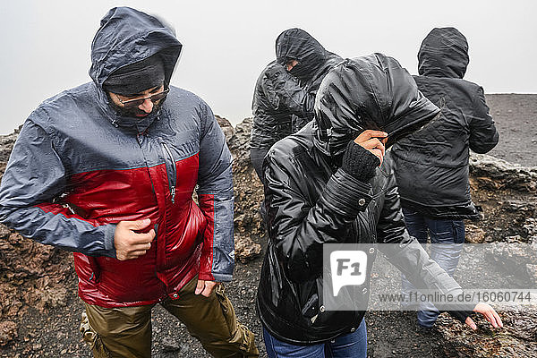 Touristen mit Kapuzenregenmänteln bei nassen und windigen Bedingungen; Snaefellsbaer  Westliche Region  Island