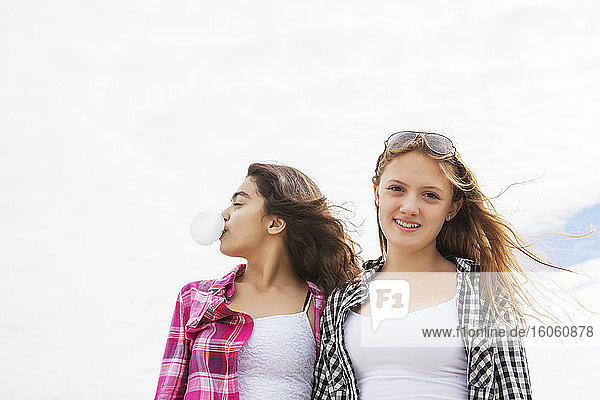Zwei Freunde stehen mit windgeblasenem Haar zusammen  einer bläst eine Blase mit Bubblegum; Toronto  Ontario  Kanada