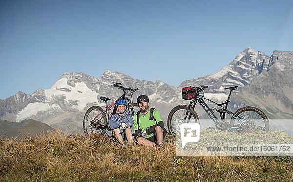 Mountainbikerpaar sitzt neben eBikes in herbstlicher Bergkulisse der Stubaier Alpen  Freizeitarena Bergeralm  Bikepark Tirol  Gries am Brenner  Tirol  Österreich  Europa