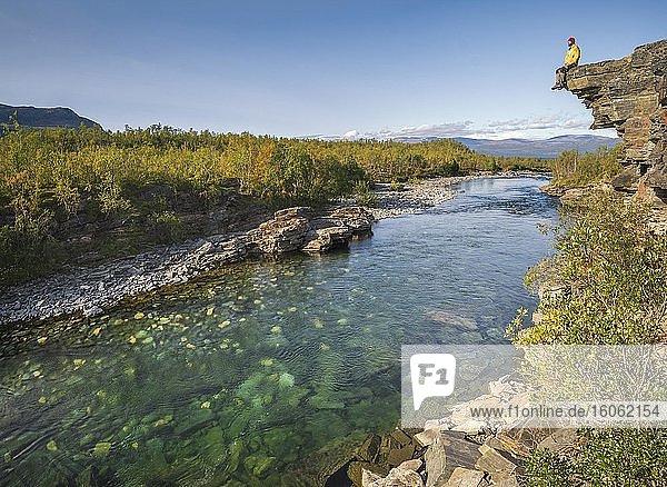 Mann sitzt auf Steinklippe über dem Fluss Abiskojåkka  Abisko Nationalpark  Lappland  Abisko  Norrbottens län  Schweden  Europa