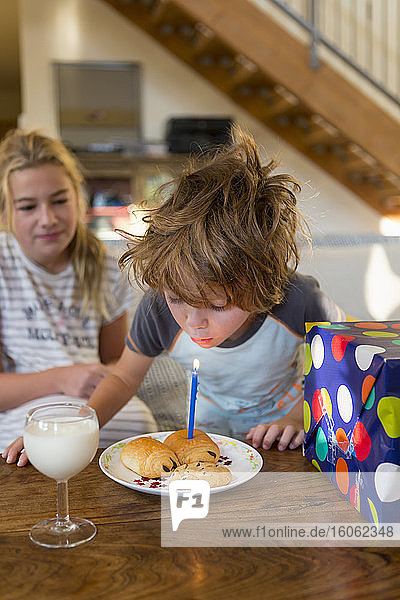 5 Jahre alter Junge bläst Kerze auf Croissant aus