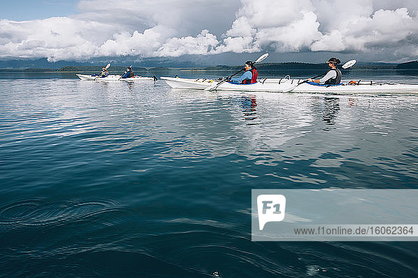 Seekajakfahrer paddeln in unberührten Gewässern einer Bucht an der Küste Alaskas.