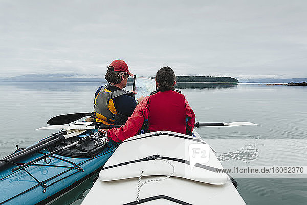 Sea kayakers looking at nautical chart and mapan inlet on the Alaska coastline.