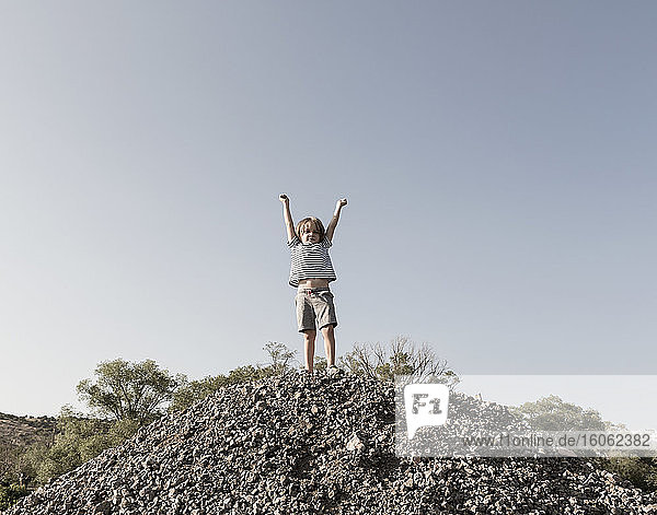 4-jähriger Junge hebt die Arme im Triumph auf dem Hügel