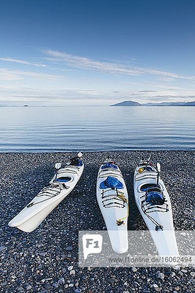 Seekajaks auf dem abgelegenen Strand und ruhigen Gewässern des Muir Inlet in der Ferne Glacier Bay National Park und Preserve Alaska