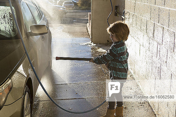 4 year old boy washing a car in car wash