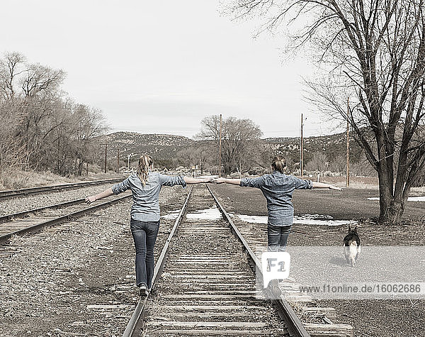 Vor-Teenager-Freundinnen  die zusammen auf Eisenbahnschienen gehen NM.