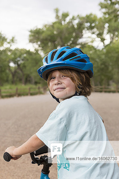 smiling 4 year old boy in a cycle helmet looking over his shoulder.