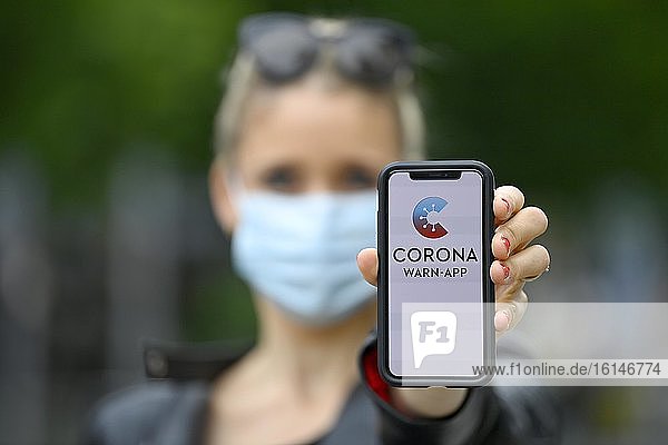 Woman with face mask  showing smartphone with Corona Warn-APP  Corona crisis  Baden-Württemberg  Germany  Europe