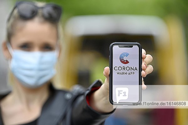 Frau mit Mundschutzmaske  zeigt Smartphone mit Corona Warn-APP  Corona-Krise  Baden-Württemberg  Deutschland  Europa