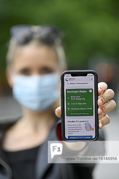 Frau mit Mundschutzmaske zeigt Smartphone mit Corona Warn-APP  niedriges Risiko  Corona-Krise  Baden-Württemberg  Deutschland  Europa
