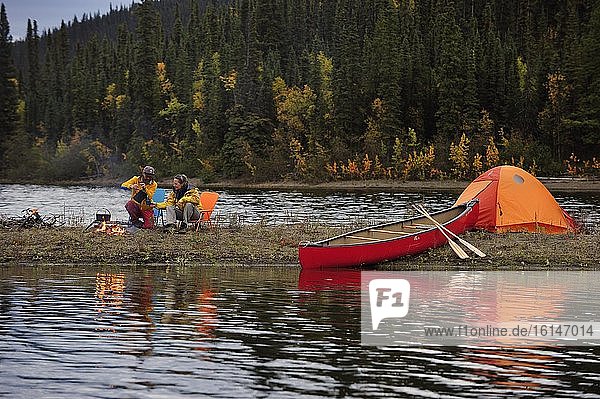 Paar am Lagerfeuer ist mit Kanu unterwegs  campt am Ufer eines Sees  Yukon Territory  Kanada  Nordamerika