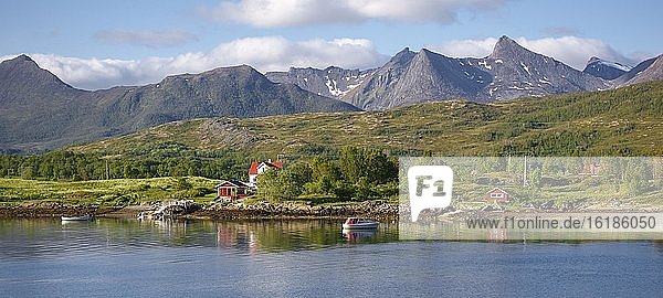 Wohnhaus mit Boot am Fjord  hinten Berggipfel  Insel Senja  Botnhamn  Troms  Norwegen  Europa