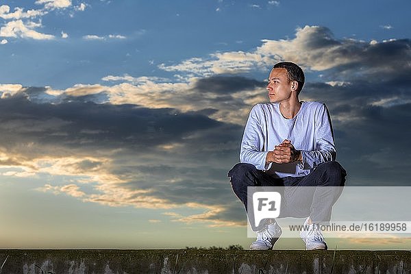 Mann  21 Jahre  sitzend  im Sonnenuntergang  Remstal  Baden Württemberg  Deutschland  Europa