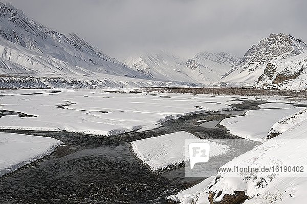 River flowing through snow covered mountains in Spiti  a high altitude frozen plateau  home of the Snow Leopards  in the Indian Himalayas  India  Asia
