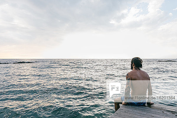 Mann am Meeresrand sitzend