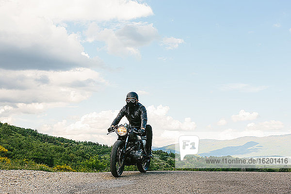Young male motorcyclist on vintage motorcycle on rural road  Florence  Tuscany  Italy