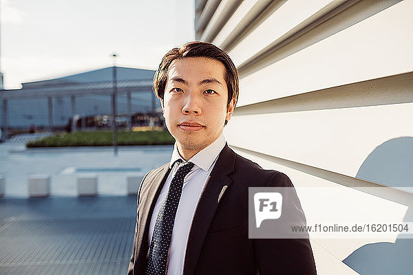 Portrait of Asian businessman wearing dark suit  looking at camera.