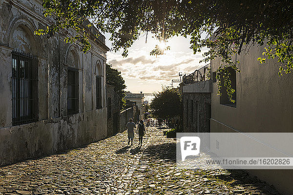 Zwei Menschen schlendern die gepflasterte Straße entlang  Barrio Historico (Altstadt)  Colonia del Sacramento  Colonia  Uruguay