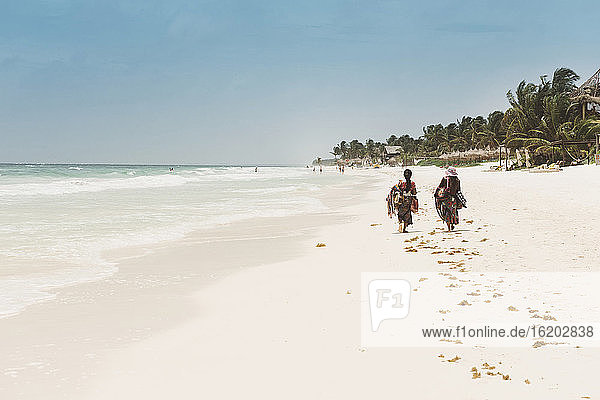 Two local people walking along beach  Tulum  Mexico