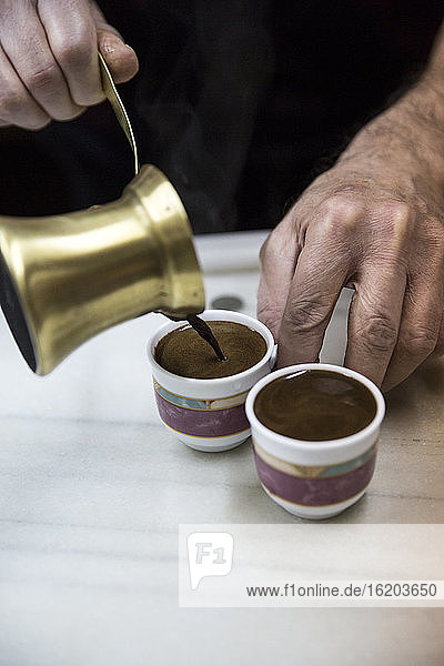 Ältere männliche Hände gießen traditionellen marokkanischen Kaffee ein